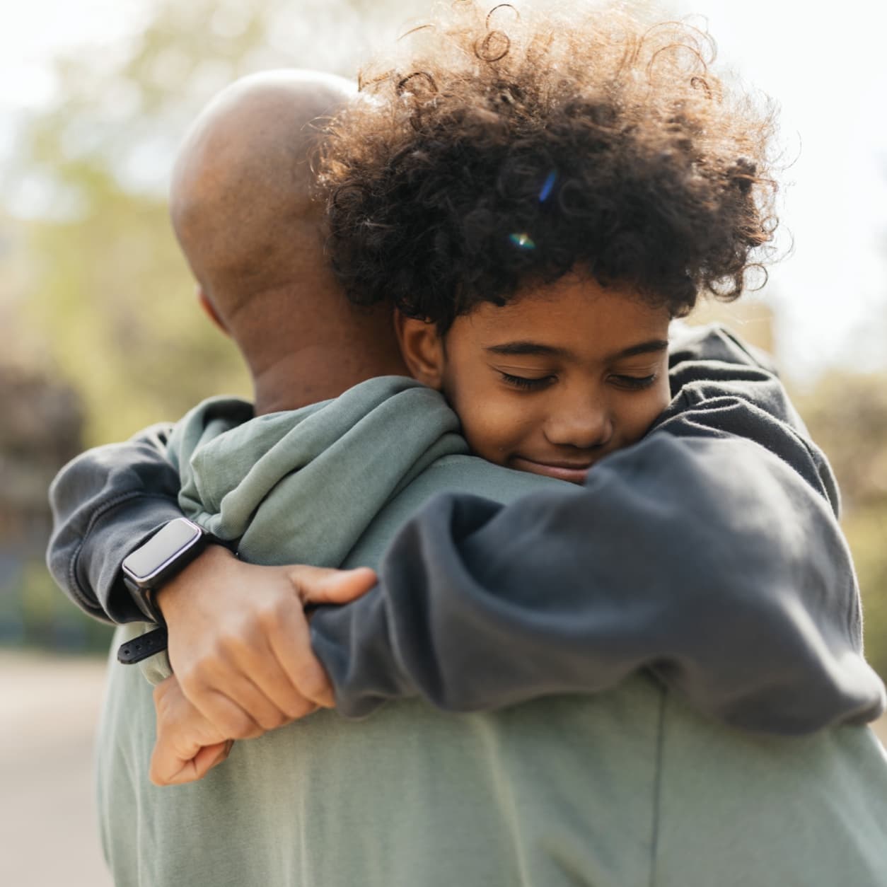 Child hugging an adult tightly with both arms around their neck