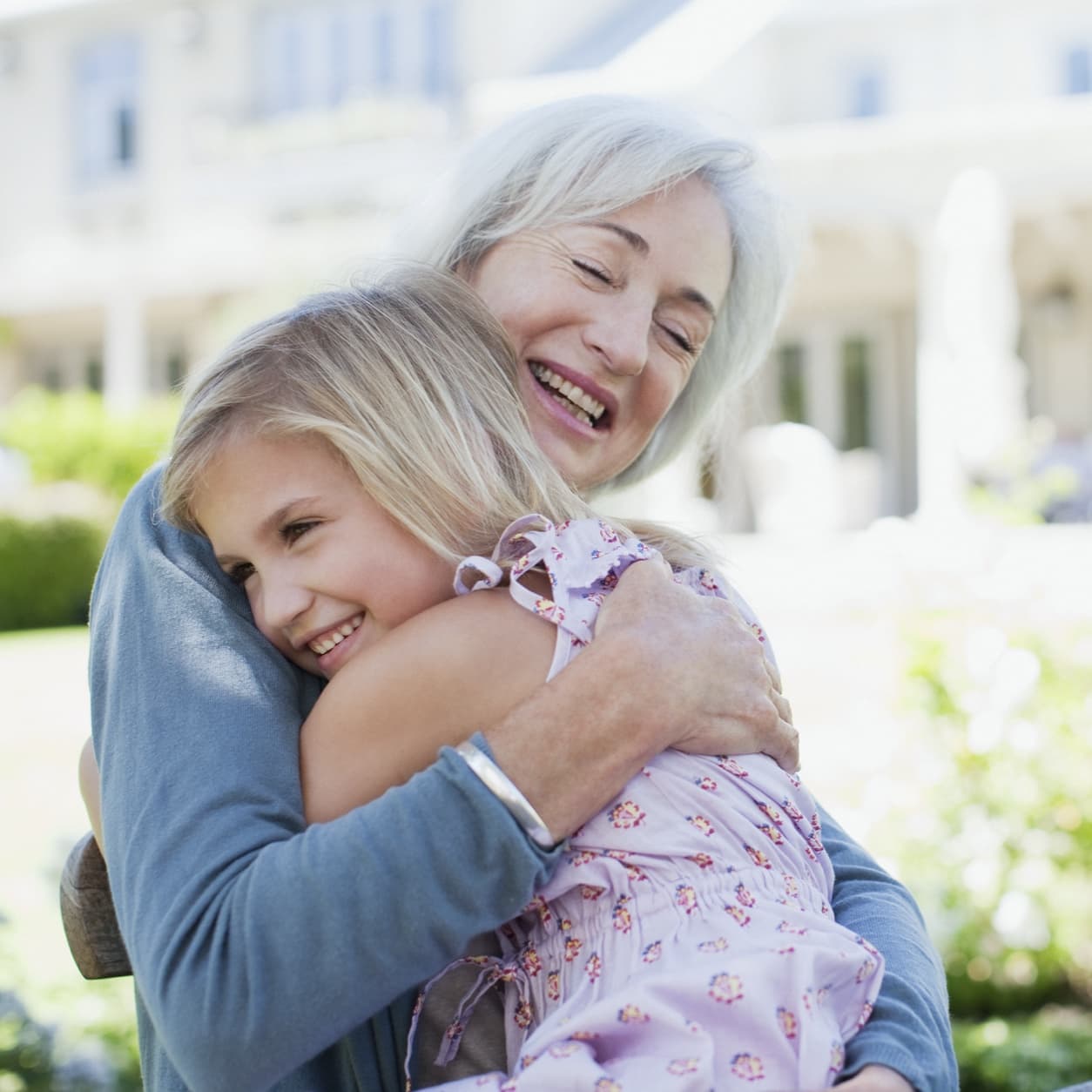 Grandmother hugging her granddaughter in a sunlit garden