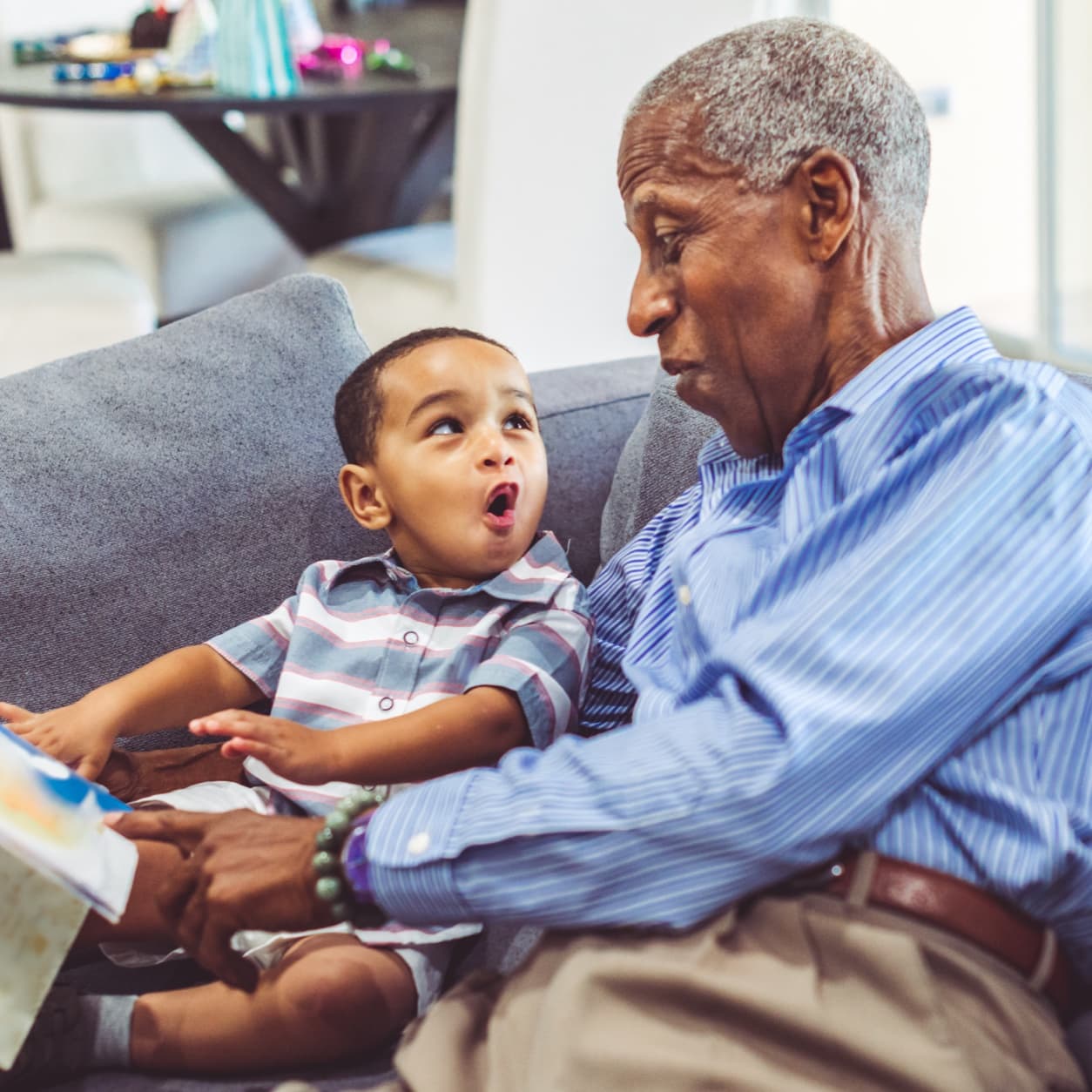 Grandfather and grandson reading a picture book together on the sofa