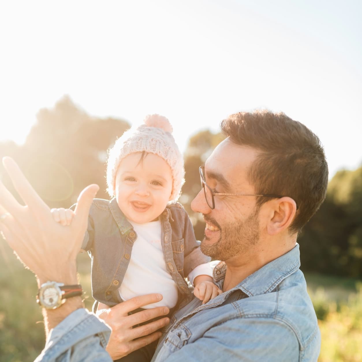 Father holding his smiling baby in a sunlit field