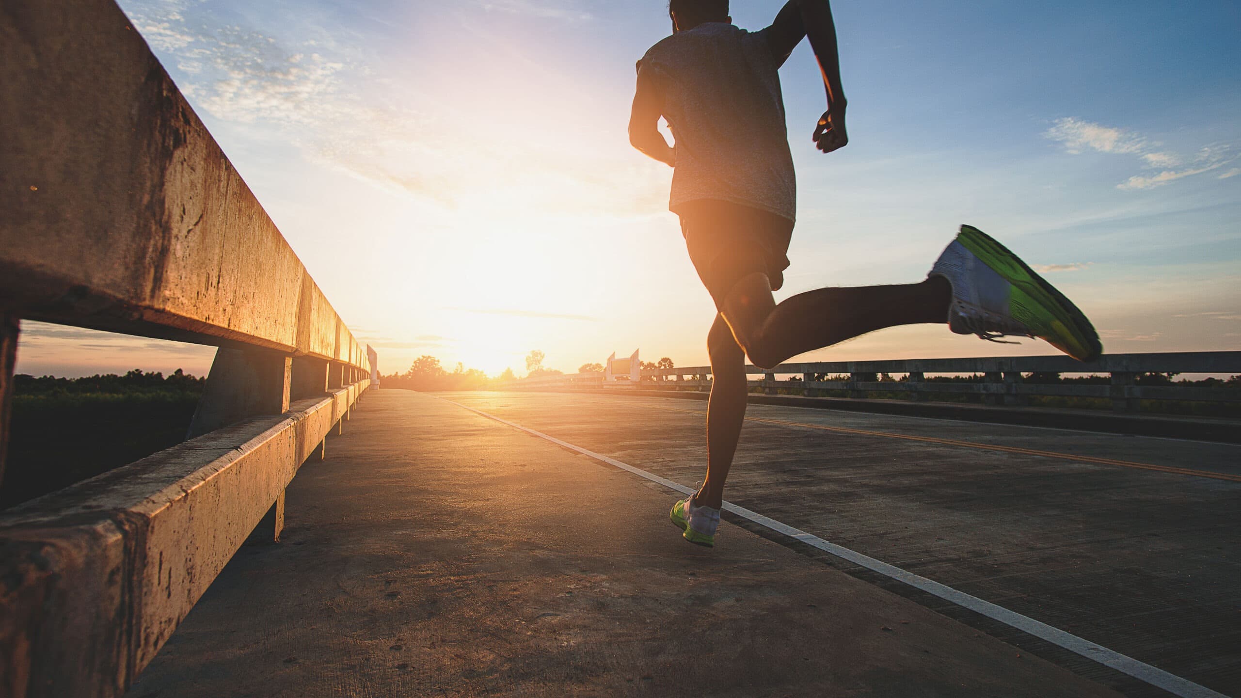 Runner in mid-stride on a road at sunrise
