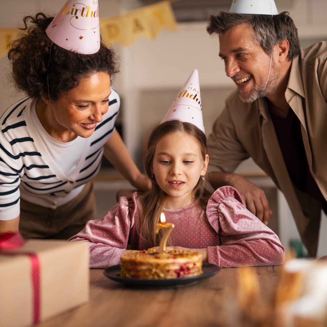 Girl blowing out a birthday candle while her parents look on